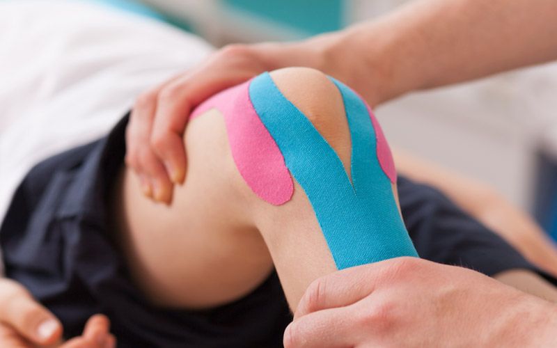 Ein Kinesio-Tape wird zur Stabilisierung des Kniegelenks angelegt